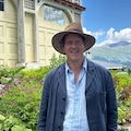 Monty Don pictured wearing a blue gardening jacket french coat smiling with a view of the hills along the rhine