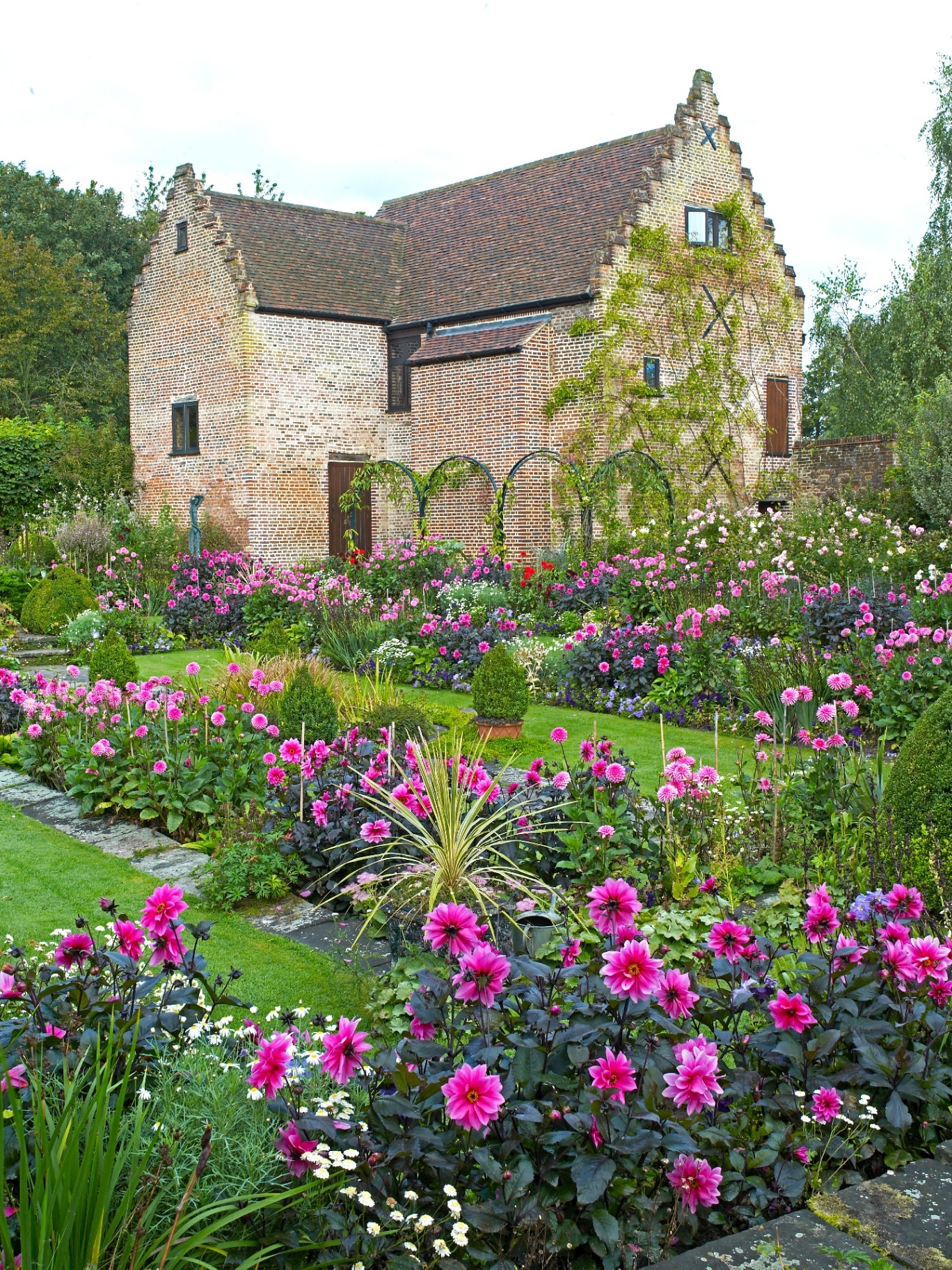 CHENIES MANOR TUDOR GARDEN AND PAVILION GALLERY, CHENIES, BUCKINGHAMSHIREM, ENGLAND, AUGUST 2014. The impressive sunken garden with a colourful display of Dahlias in late summer and the Tudor Pavilion